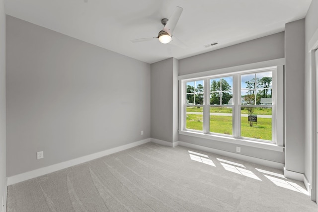 spare room with light carpet, ceiling fan, visible vents, and baseboards