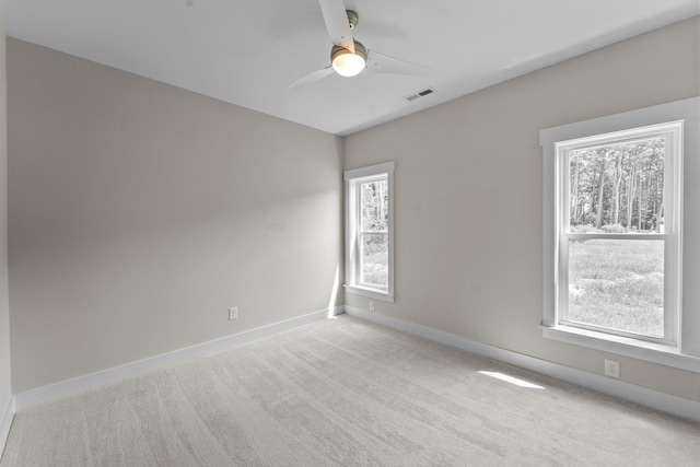 unfurnished room with light colored carpet, a healthy amount of sunlight, and visible vents