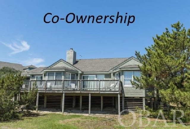 back of property with a chimney and a deck