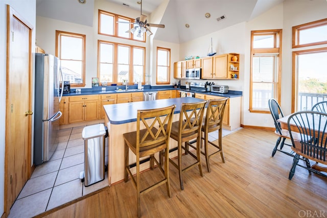 kitchen featuring a center island, open shelves, stainless steel appliances, dark countertops, and a kitchen breakfast bar