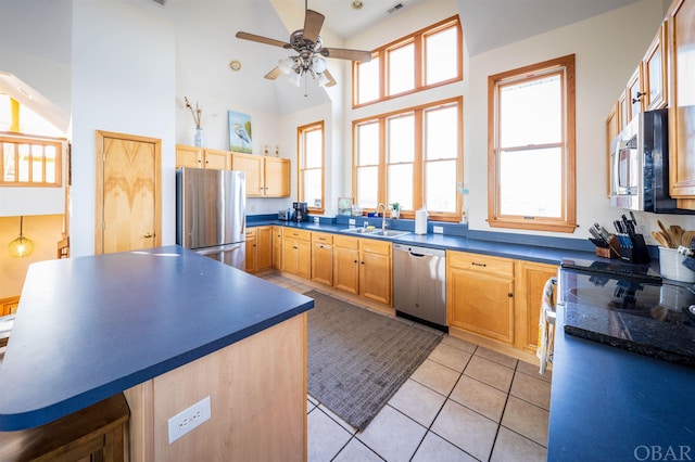 kitchen featuring appliances with stainless steel finishes, dark countertops, a sink, and light tile patterned floors