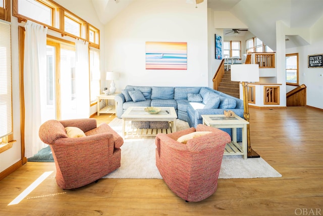 living room featuring stairs, high vaulted ceiling, wood finished floors, and baseboards