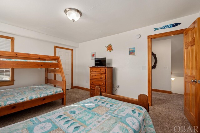 bedroom with dark carpet and baseboards