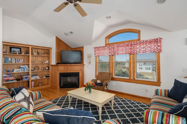 living room featuring a large fireplace, wood finished floors, a ceiling fan, baseboards, and vaulted ceiling