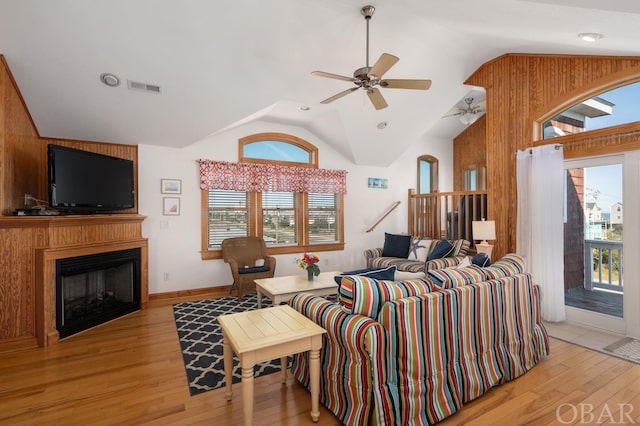 living area with lofted ceiling, visible vents, a fireplace, and light wood finished floors