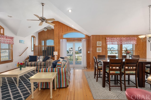 dining space with lofted ceiling, ceiling fan with notable chandelier, plenty of natural light, and light wood-style floors