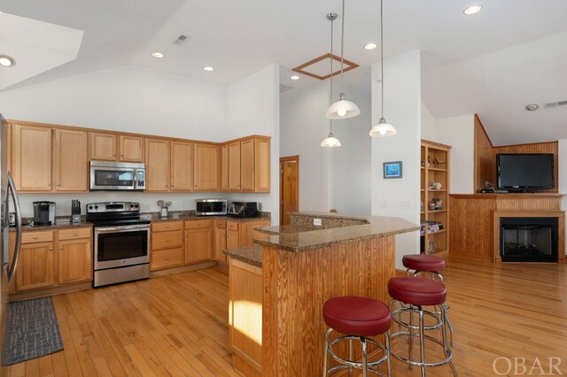 kitchen with stainless steel appliances, light wood-type flooring, pendant lighting, and a kitchen breakfast bar