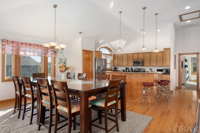 dining space featuring light wood-style floors, baseboards, visible vents, and high vaulted ceiling