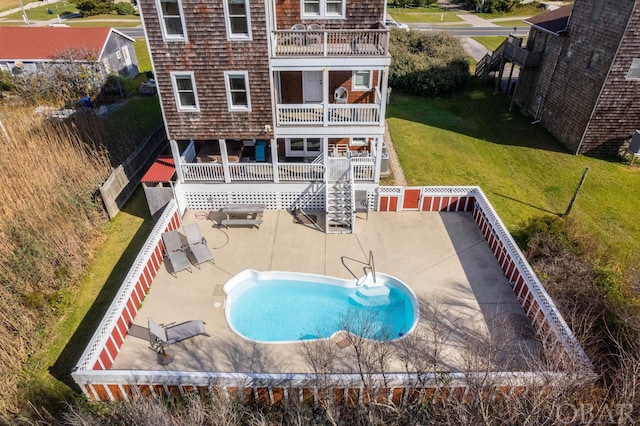 rear view of house with an outdoor pool, a lawn, a balcony, a fenced backyard, and a patio area