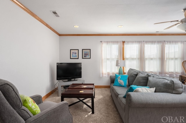 carpeted living room with baseboards, a ceiling fan, visible vents, and crown molding