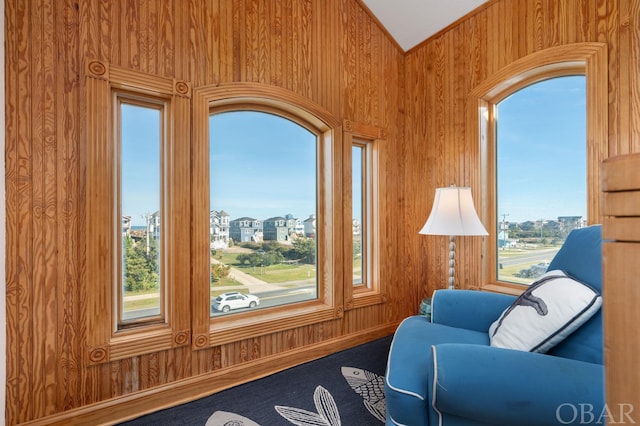 sitting room featuring wooden walls and vaulted ceiling