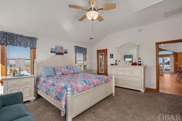 bedroom with lofted ceiling, dark carpet, visible vents, and a ceiling fan