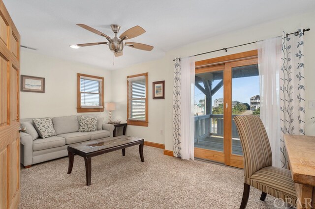 living area with a ceiling fan, light colored carpet, visible vents, and baseboards