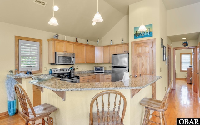 2132 Dolphin Ln Lot 62, Corolla, NC 27927 - kitchen with appliances with stainless steel finishes, plenty of natural light, a kitchen bar, light wood-type flooring, and high vaulted ceiling