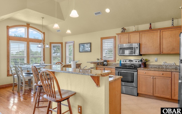 2132 Dolphin Ln Lot 62, Corolla, NC 27927 - kitchen featuring appliances with stainless steel finishes, lofted ceiling, a kitchen breakfast bar, hanging light fixtures, and a center island