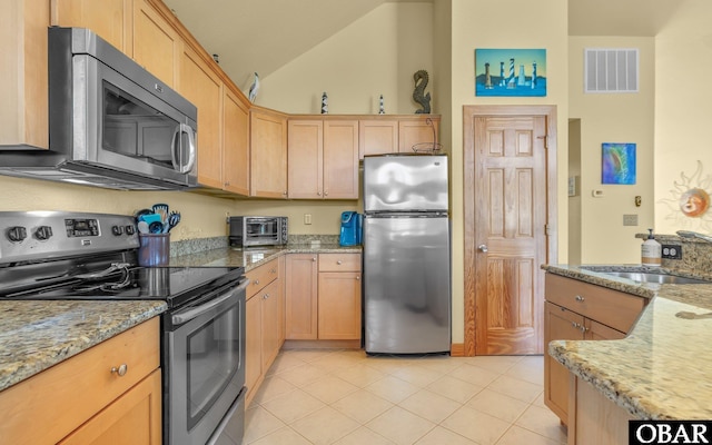 2132 Dolphin Ln Lot 62, Corolla, NC 27927 - kitchen with stainless steel appliances, light brown cabinetry, lofted ceiling, light tile patterned flooring, and light stone countertops