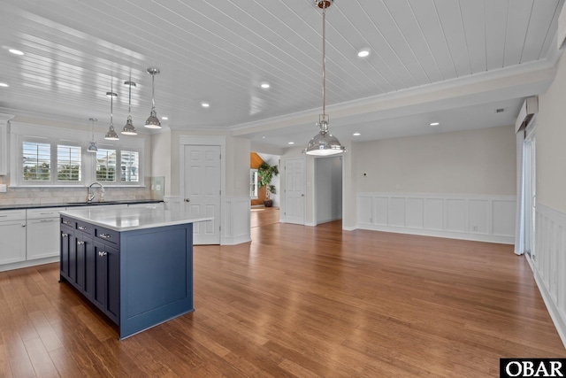 kitchen featuring a sink, backsplash, a kitchen island, wood finished floors, and wooden ceiling