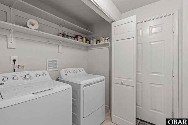 laundry room with laundry area, washing machine and dryer, visible vents, and a textured ceiling