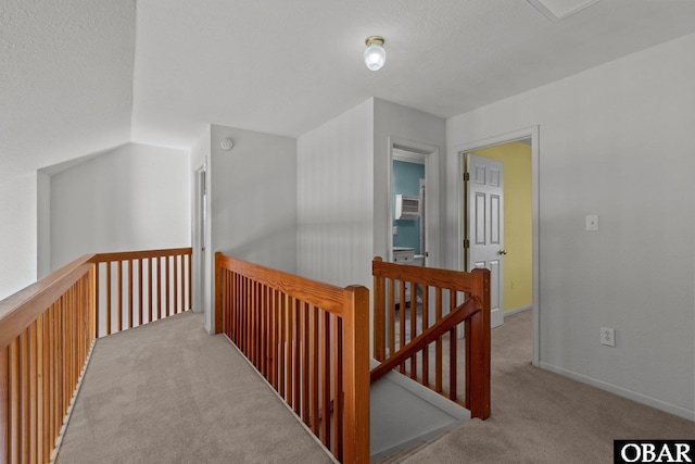 hall featuring an upstairs landing, carpet flooring, and baseboards