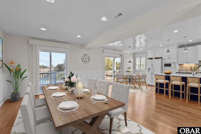 dining room with a wainscoted wall, visible vents, recessed lighting, light wood-style floors, and a decorative wall