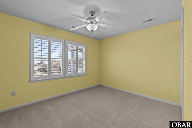 spare room featuring visible vents, a ceiling fan, a textured ceiling, carpet flooring, and baseboards