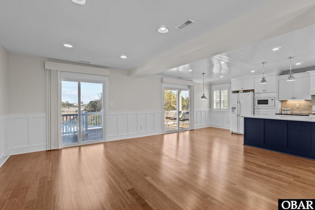 unfurnished living room with a wainscoted wall, recessed lighting, visible vents, and light wood-type flooring