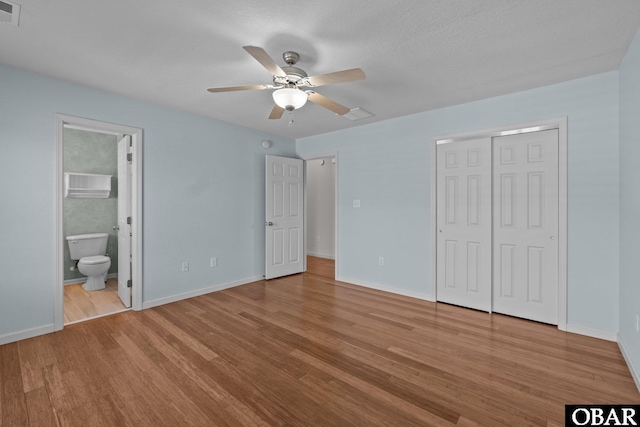 unfurnished bedroom with a closet, visible vents, baseboards, and wood finished floors