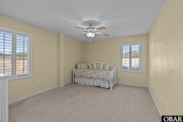 unfurnished bedroom featuring a textured wall, ceiling fan, baseboards, and carpet floors