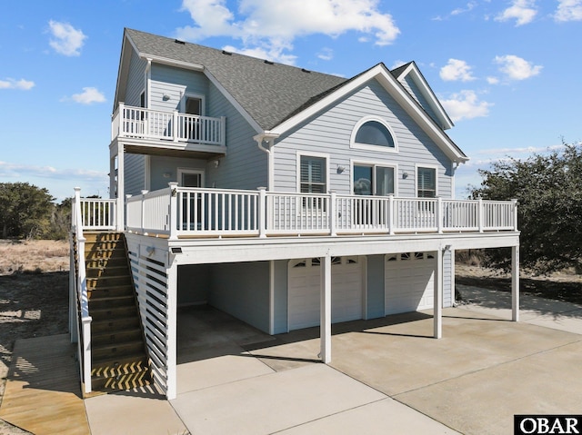 view of front of house featuring a garage, driveway, stairs, and roof with shingles