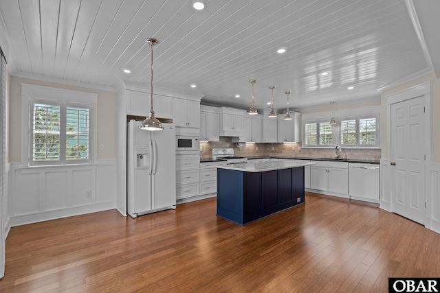 kitchen with white appliances, wood finished floors, crown molding, and tasteful backsplash