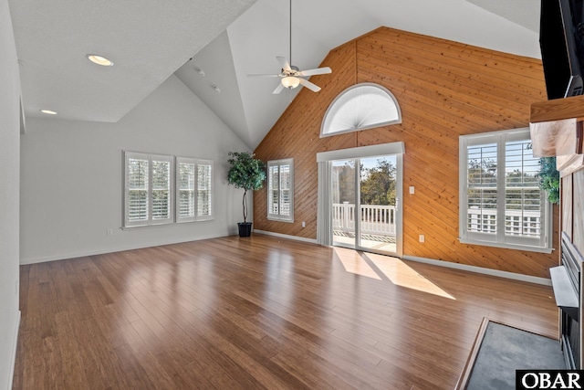 unfurnished living room featuring a wealth of natural light, high vaulted ceiling, and wood finished floors