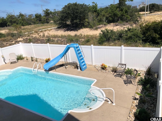 view of pool featuring a fenced in pool, a water slide, a fenced backyard, and a patio area