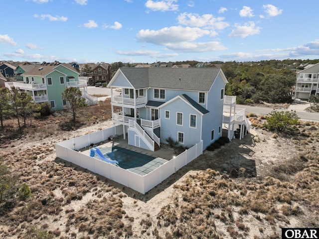 back of house featuring stairway, a balcony, a residential view, and a fenced backyard