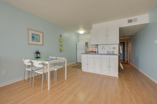 kitchen featuring visible vents, white cabinetry, freestanding refrigerator, and light wood-style floors