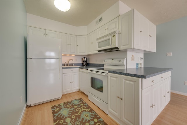 kitchen featuring light wood-type flooring, visible vents, dark countertops, white cabinetry, and white appliances