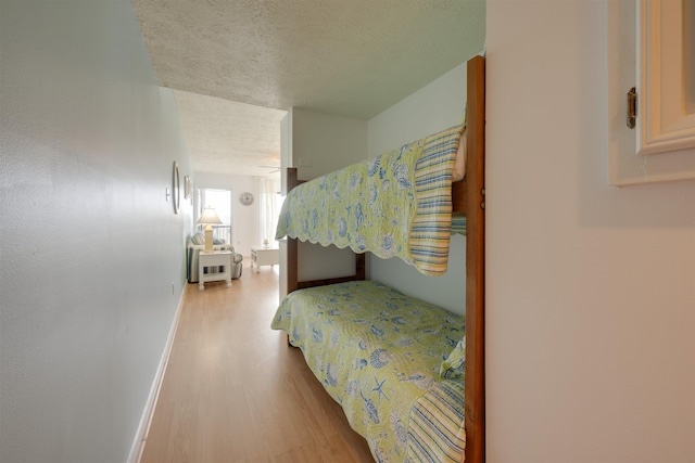 bedroom featuring a textured ceiling, baseboards, and wood finished floors