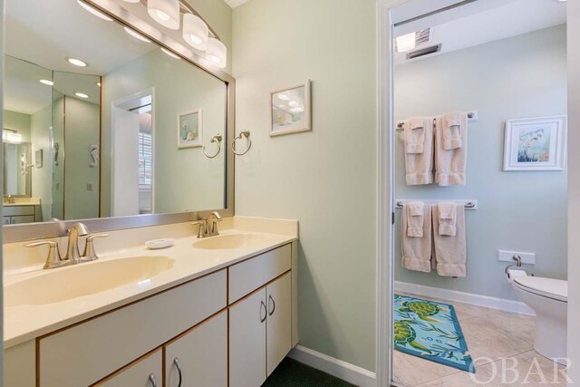 full bath with baseboards, double vanity, a sink, and tile patterned floors