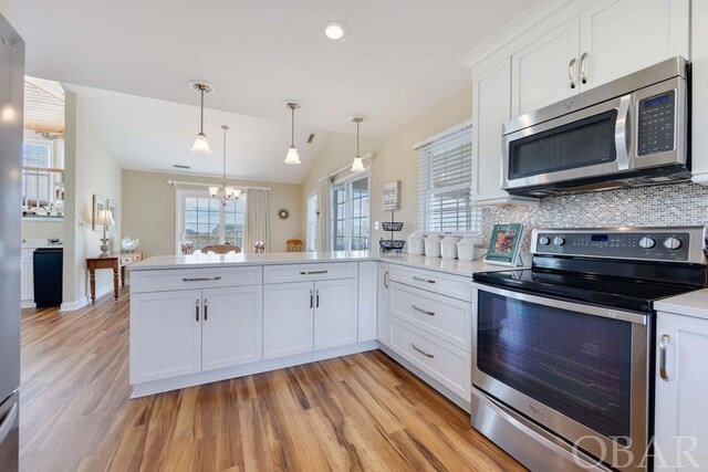 kitchen with stainless steel appliances, white cabinets, light countertops, and hanging light fixtures