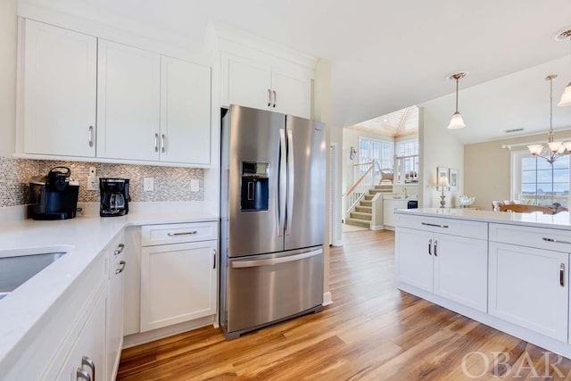 kitchen featuring decorative light fixtures, tasteful backsplash, light countertops, white cabinetry, and stainless steel fridge with ice dispenser