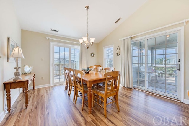 dining area featuring lofted ceiling, an inviting chandelier, light wood-type flooring, and visible vents