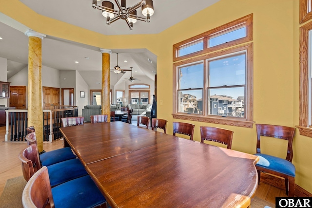 dining space with ornate columns, vaulted ceiling, wood finished floors, and ceiling fan with notable chandelier