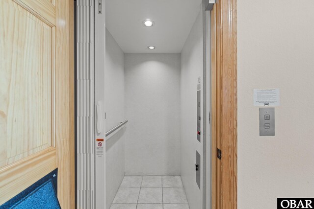 hallway featuring recessed lighting, light tile patterned flooring, and elevator