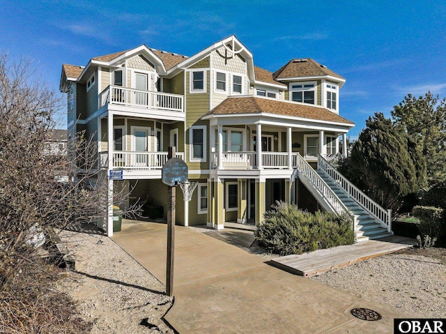 view of front facade featuring a balcony, a carport, a porch, and concrete driveway