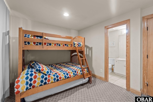 bedroom with ensuite bathroom, baseboards, and light colored carpet