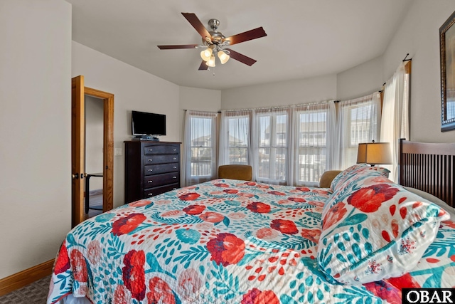 bedroom featuring ceiling fan, multiple windows, and baseboards