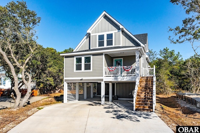 coastal inspired home with driveway, board and batten siding, stairway, covered porch, and a carport