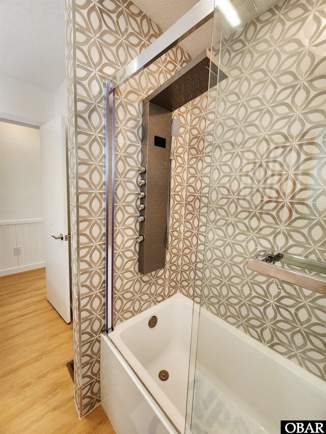 bathroom featuring a wainscoted wall, a textured ceiling, wood finished floors, and shower / bathtub combination