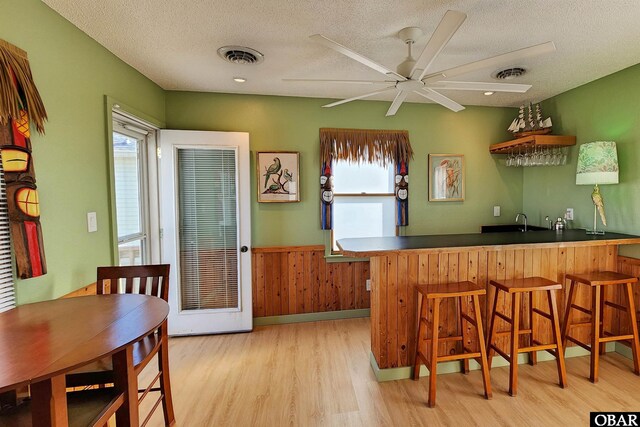 kitchen featuring a peninsula, a breakfast bar, wainscoting, and visible vents