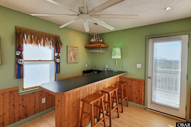 kitchen featuring a peninsula, a wainscoted wall, a breakfast bar area, and wood walls