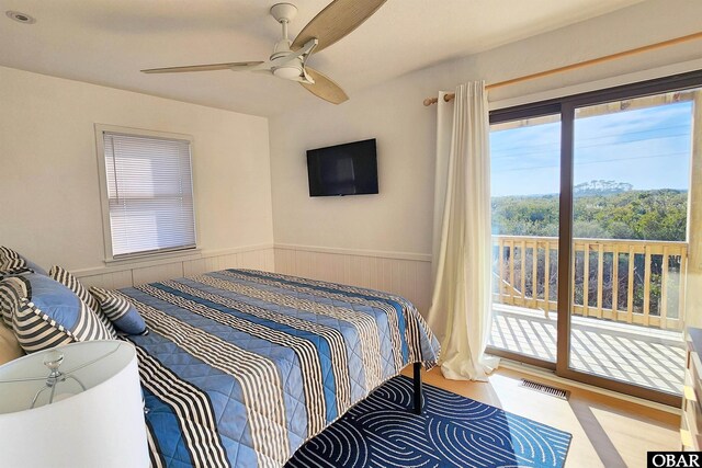 bedroom with a ceiling fan, access to outside, wainscoting, and visible vents